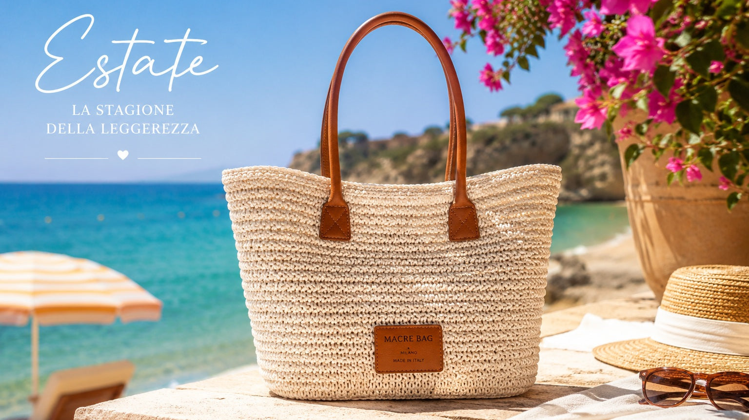 Borsa tote Macrè Bag in raffia color crema con manici in pelle su muretto vista mare, bouganville rosa, cappello di paglia e occhiali da sole — estate