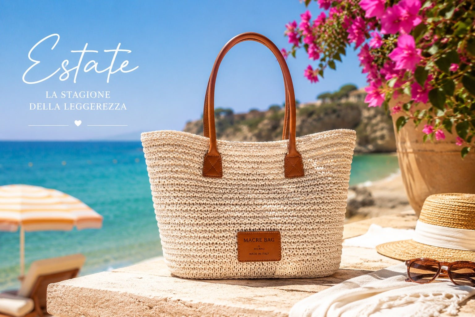 Borsa tote Macrè Bag in raffia color crema con manici in pelle su muretto vista mare, bouganville rosa, cappello di paglia e occhiali da sole — estate